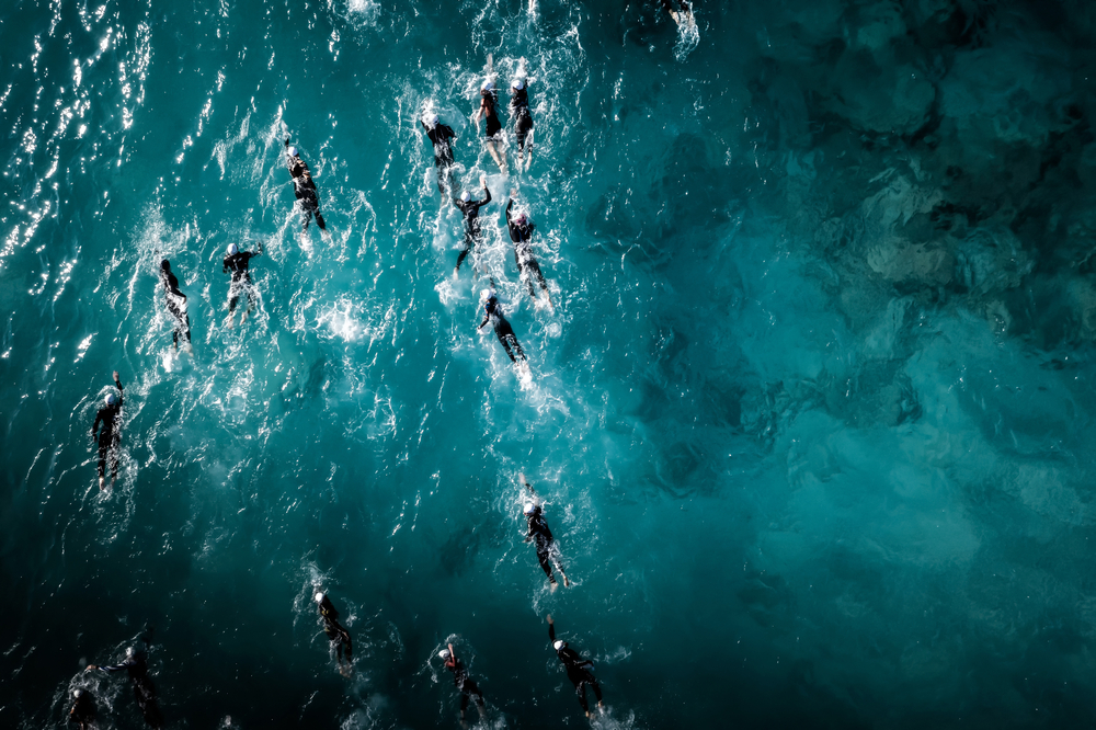 A group of triathlon swimmers in the ocean seen from above