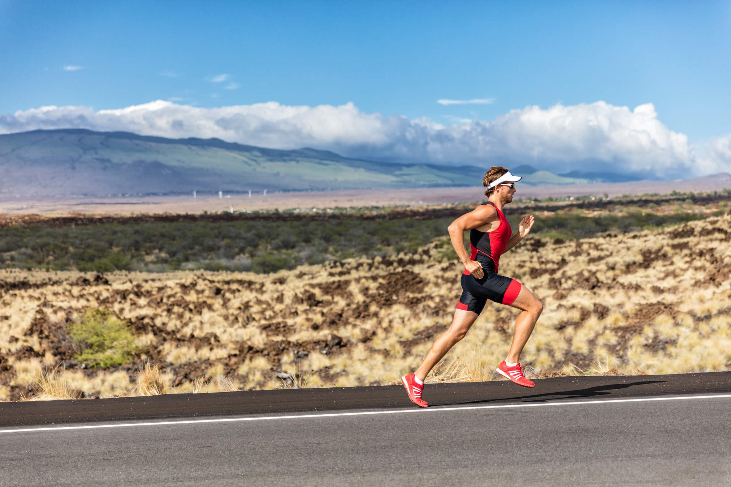 a triathlete runs along a road against a wild landscape