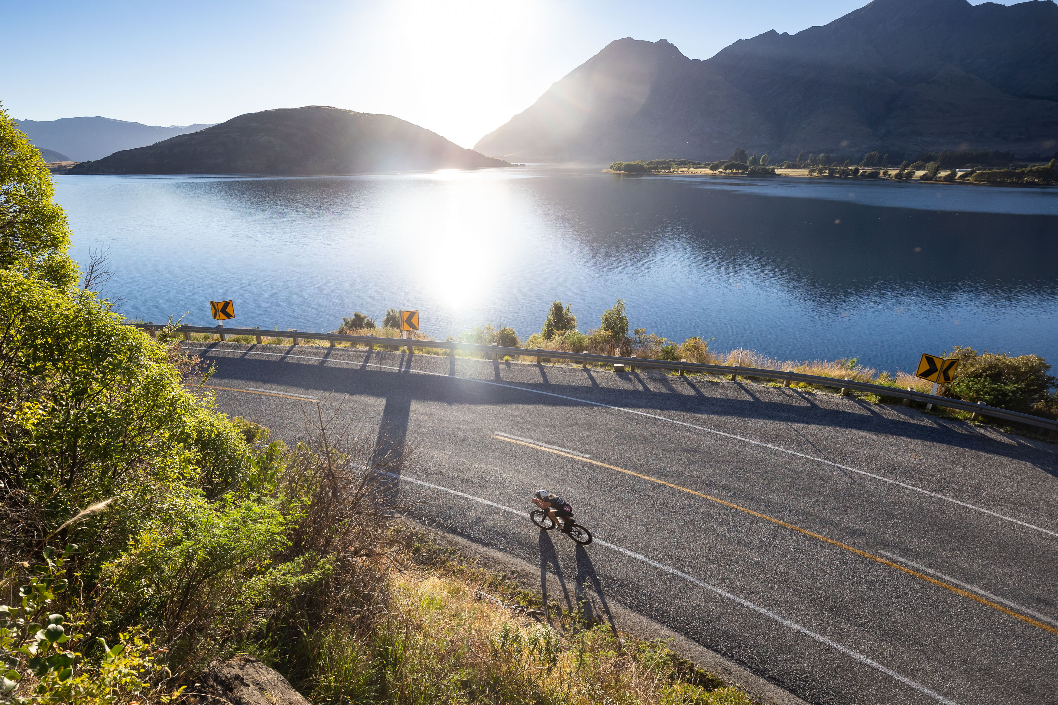 Triathlon cyclist riding on road beside lake