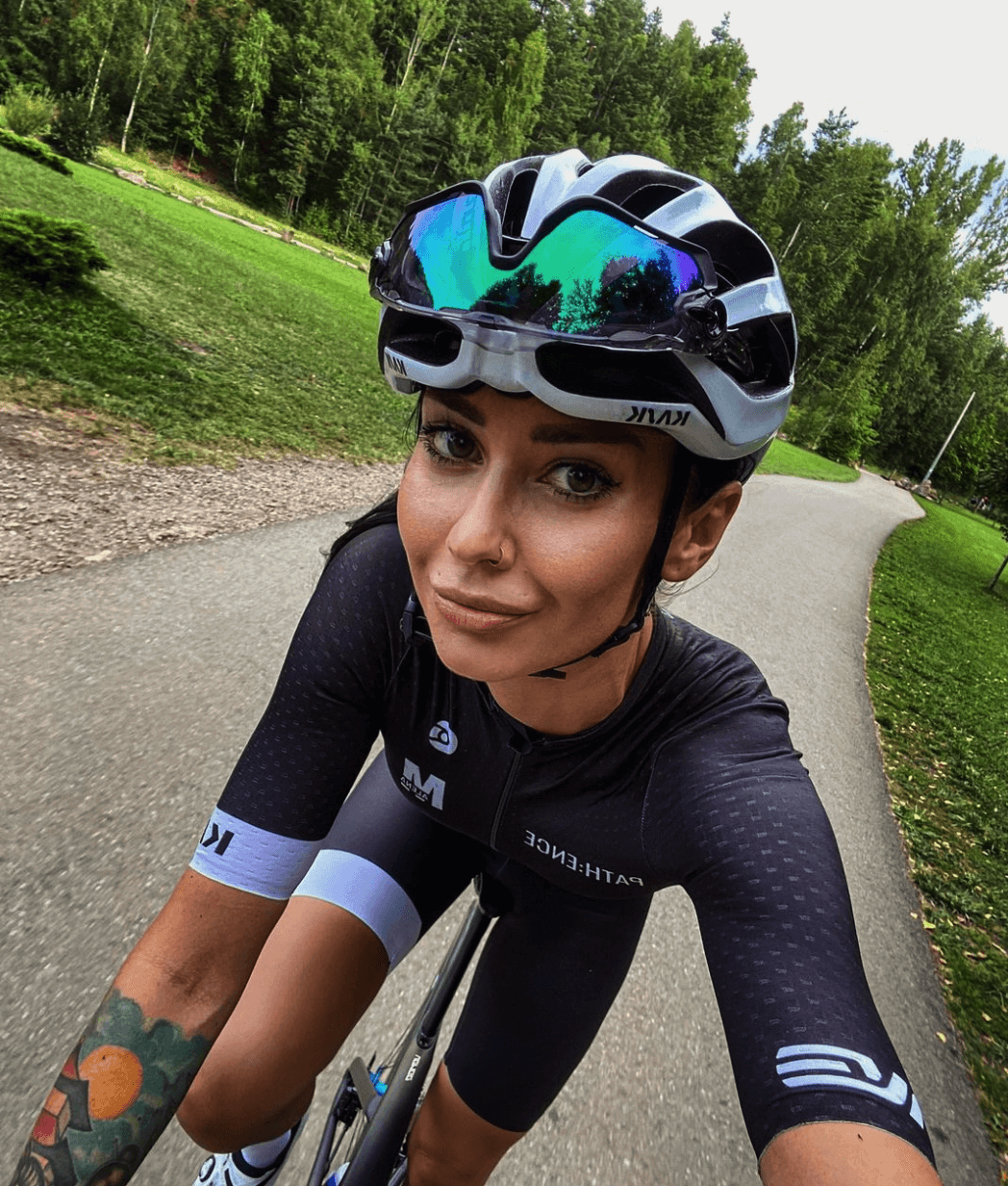 ROUVY Ambassador Malena Nowotarska riding her bike on a narrow tarmac road in the forest
